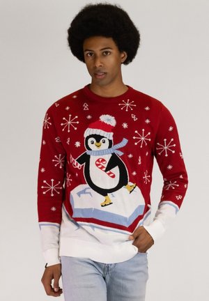 Red Christmas sweater with a penguin design, featuring white snowflakes and a blue scarf. Made from soft fabric with ribbed cuffs and hem.