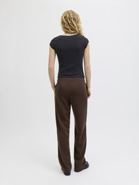 Camiseta negra ajustada de manga corta, combinada con pantalones de pierna ancha marrones. Material suave con una silueta relajada, que presenta una cinturilla discreta.