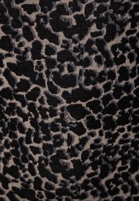 Musta ja beige leopardi kuvioinen tekstiili, jossa on epäsäännöllisiä muotoja ja teksturoitu pinta. Tausta on pääasiassa musta, jossa on vaaleampia korostuksia.
