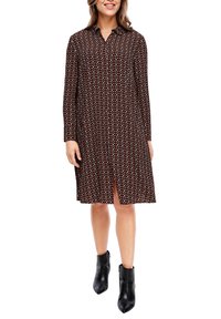 Burgundy dlouhá šaty s geometrickým vzorem, zapínání na knoflíky vpředu a boční rozparek; nošeno s černými kotníkovými botami. Hladká struktura látky.