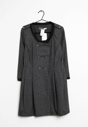 Robe grise à motif avec un col rond, des manches longues, des boutons devant à double boutonnage et une jupe plissée. Accrochée à un crochet noir.