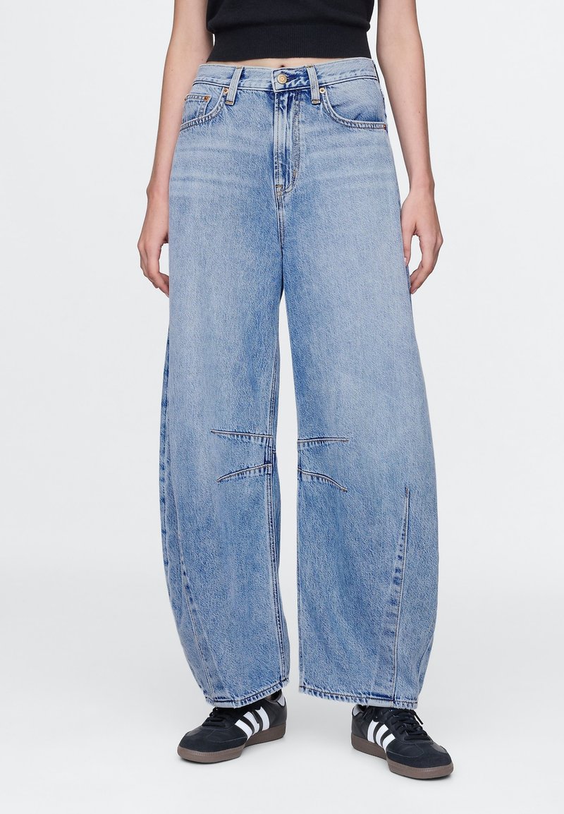 Pantalones vaqueros anchos de pierna en azul claro con cintura alta, con bajo deshilachado, detalles sutiles de desgaste y diseño tradicional de cinco bolsillos. Hechos de mezclilla.