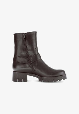 Black leather ankle boot with a side zipper, a wide strap across the upper, and a chunky, textured sole with cut-out details.