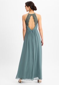 Teal maxi-jurk met een kant achterzijde en een open ontwerp. Vloeiende stof met een getailleerde taille. Gladde textuur, elegante silhouet.