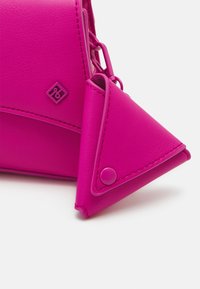 Lyserød syntetisk lædertaske med en trekantet møntpung. Funktioner en glat tekstur, en trykknaplukning og præget logo detaljer.