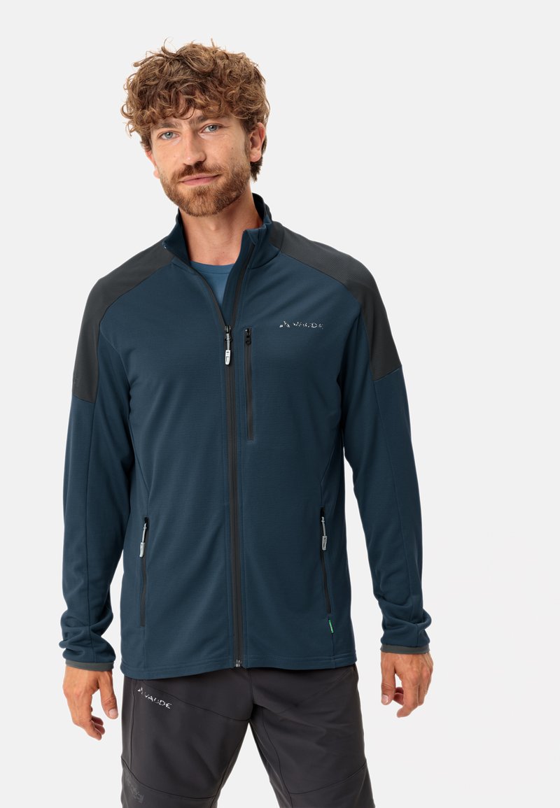 Giacca leggera da uomo di colore blu scuro con accenti neri sulle spalle, cerniera integrale e due tasche anteriori con chiusura a cerniera.