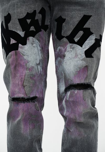 Γκρι τζιν από τζιν ύφασμα με μαύρο κείμενο σε στυλ γκράφιτι και μοτίβα από μωβ λουλούδια, με σκισμένα γόνατα.