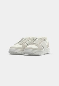 White sneakers with gray suede accents, lace closure, perforated toe box, and textured rubber sole. Features subtle side stripes.