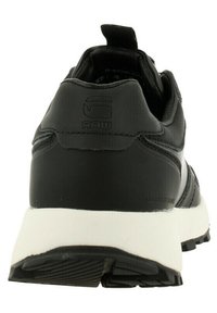 Czarno-białe sneakersy G-Star RAW widziane z tyłu, z teksturowaną podeszwą i pętlą na kołnierzu pięty.