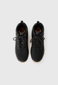 Black hiking shoes with a textured upper, round laces, metal eyelets, and a brown rubber sole. Dual pull tabs on the tongue and heel.