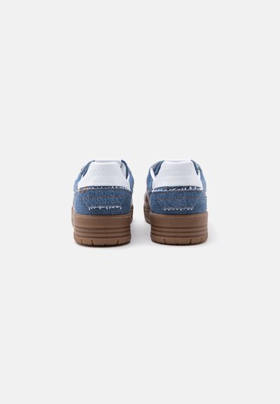 Ζευγάρι τζιν sneakers με καφέ λαστιχένιες σόλες, εμφανιζόμενα από πίσω, με λευκές φτέρνες με ανάγλυφο το όνομα της μάρκας Moschino.