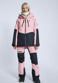 Skitjakke og -bukser i sæt, med et pink og sort farveblokdesign. Fremstillet af et struktureret, vandtæt materiale med hætte og lynlåse.