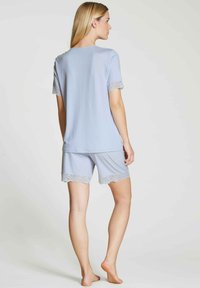Lichtblauw pyjamapak met een top met korte mouwen en shorts. De kantafwerking aan de mouwen en onderrand voegt een verfijnde detail toe. Zachte stofstructuur.