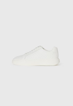 White sneaker with a textured upper featuring a diamond pattern, rounded toe, and flat rubber sole. Lace-up design with minimal accents.