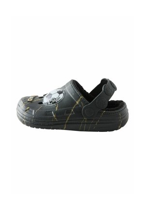 Schwarzer Slip-on-Clog mit gelben Streifen, einer Fußball-Dekoration oben und einem flauschigen Innenfutter mit verstellbarem Fersenriemen.