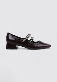 Zapato estilo Mary Jane de charol negro con punta afilada, dos correas con hebilla y un tacón bajo cuadrado. Textura suave con un acabado brillante.
