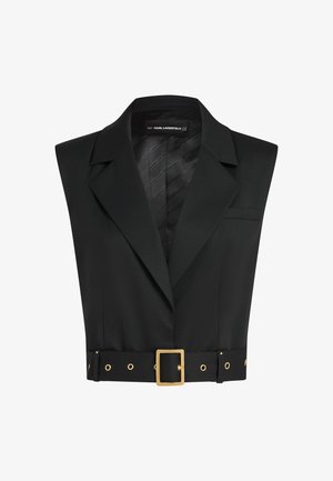 Crna bezrukava bluzica s oštrim kragnom i remenom, koji ima zlatnu kvadratnu kopču i detalje s rupicama na remenu. Glatka tekstura tkanine.