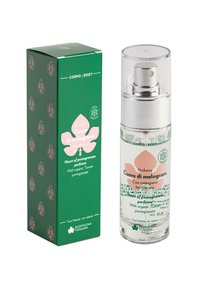 Cartone verde con motivo di melograno accanto a una bottiglia spray in vetro trasparente con tappo argentato, etichettata "Cuore di melograno" in testo rosa e bianco.