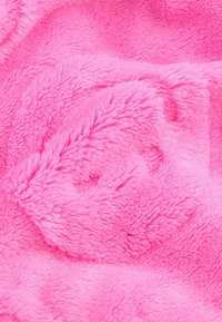 Couverture en fausse fourrure rose avec une surface douce et texturée, présentant un design en poils longs et moelleux ainsi que des motifs de vagues subtils tout au long.