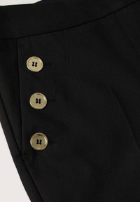 Zwarte stoffen broek met drie grote, glanzende gouden knopen langs de zijkant, met een gladde textuur en een stijlvolle snit.