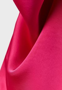 Tissu soyeux rose vif avec des plis lisses et une texture douce, se courbant naturellement sur un fond gris clair.
