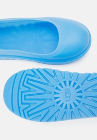 Blue rubber slip-on shoe with a rounded toe and textured outsole. Features a smooth upper and ridged sole for grip and comfort.