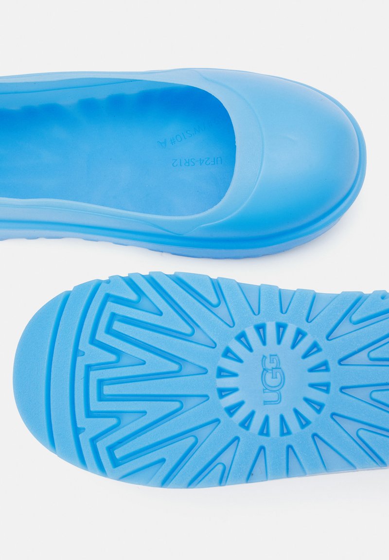 Niebieski gumowy but wsuwany z zaokrąglonym czubkiem i teksturowaną podeszwą. Posiada gładką cholewkę oraz żłobioną podeszwę zapewniającą przyczepność i komfort.