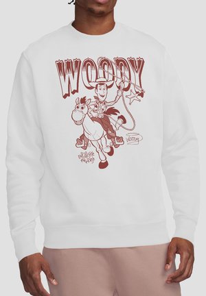 Man wearing white sweatshirt with a brown sketch of Woody riding Bullseye, holding a lasso, with large text "Woody" above.