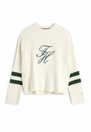 Krämfärgad stickad tröja med kabelmönster, med gröna randiga detaljer på ärmarna och en broderad "FH"-logotyp på framsidan.