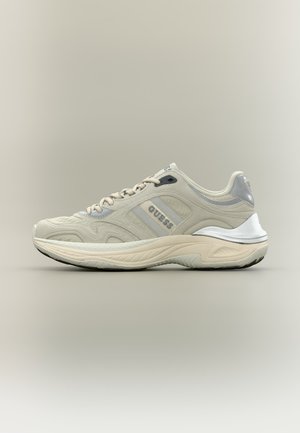 Sneaker Guess beige con suola spessa, tomaia in mesh e pelle, design con lacci e dettaglio argentato sul tallone su uno sfondo neutro.