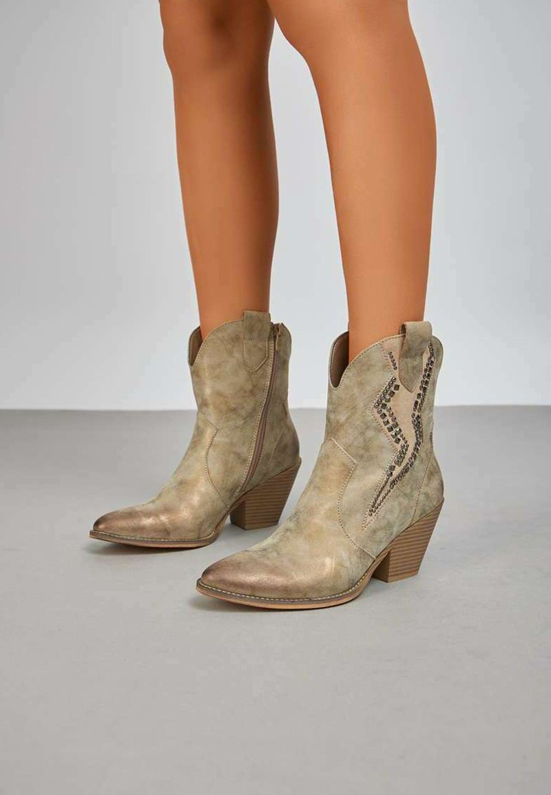 Bottes de cowboy en cuir tan avec un bout pointu, un talon angulé et une broderie décorative en motif zigzag. Zips latéraux pour un enfilage facile.