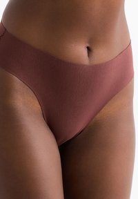 Culotte de bikini brun sans couture avec une finition mate douce et une large ceinture élastique, offrant une coupe basse pour le confort et l'ajustement.