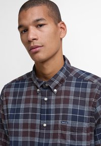 Męska koszula w kratę na guziki w kolorze ciemnoniebieskim, szarym i bordowym. Posiada klasyczny kołnierzyk oraz małą kieszonkę na piersi z logo.