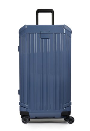 Maleta rígida azul con relieves verticales, asa telescópica negra, cuatro ruedas giratorias negras y pequeño panel con logo en la parte superior.