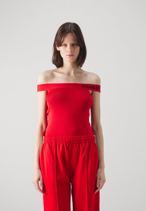 Haut rouge à encolure dénudée en maille côtelée avec le logo noir "HUGO", associé à un pantalon de survêtement rouge ample avec une taille froncée et des bandes latérales.