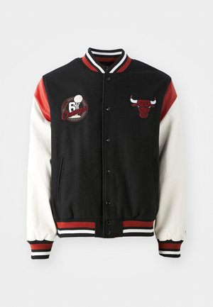 Fekete és piros sportdzseki fehér ujjal, hímezett logókkal, gombos záródással és csíkos bordás mandzsettával és aljjal.