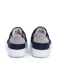 Marineblaue Canvas-Schuhe mit einer glatten grauen Wildleder-Fersenpartie, weißer Gummisohle und gesticktem Branding auf der Ferse. Niedriggeschnittenes Design.