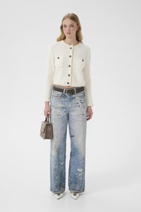 Bílý pletený kardigan s kulatým výstřihem a dvěma předními kapsami, doplněný o vybledlé, oprané modré džíny. Malá hnědá kabelka, špičatá obuv.