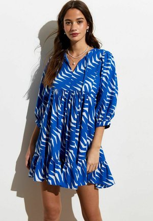 Blauwe jurk met witte zebra-strepen, V-hals, lange mouwen, geplooide taille en gerimpelde zoom. Soepele stoftextuur.