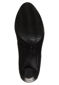 Semelle de chaussure noire avec des lignes texturées et une forme arrondie. Présente une finition lisse et un petit accent circulaire près de la section du talon.