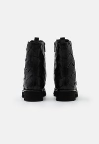 Stivali alla caviglia in pelle nera con texture intrecciata, dotati di una suola spessa e cerniere laterali per una facile calzata.