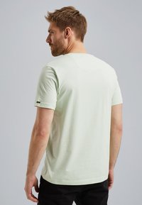 Lys grøn kortærmet t-shirt lavet af blødt bomuld. Har en rund halsudskæring og et lille mærke på venstre ærme. Glat tekstur.
