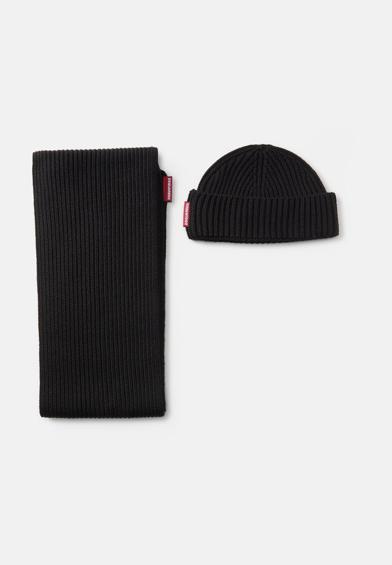Cachecol e gorro de malha canelada pretos, com uma textura espessa, ambos com pequenas etiquetas de marca vermelhas, apresentando um design simples e um ajuste acolhedor.