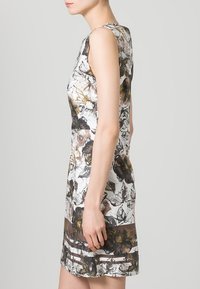 Vestido sin mangas con un estampado floral en tonos tierra sobre un fondo blanco, con una silueta ajustada y un corte recto.