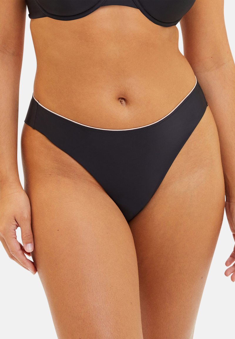 Bas de bikini noir avec un tissu lisse et extensible, à taille basse, accentué par une fine bordure contrastante le long de la taille.
