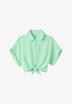 Camicia verde chiaro a maniche corte con bottoni, colletto, tasca frontale sul petto e nodo annodato all'orlo, mostrata su sfondo bianco.
