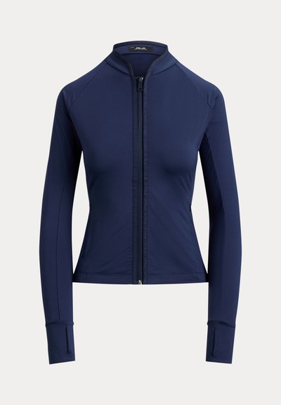 Γυναικείο στενό σακάκι σε ναυτικό μπλε χρώμα με μακριά μανίκια, φερμουάρ στο μπροστινό μέρος, γιακά τύπου mock neck και τρύπες για τον αντίχειρα στα μανίκια.