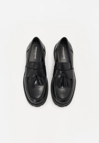 Mocasines de cuero negro con un acabado suave, que presentan un fleco decorativo y un diseño cosido. Punta redondeada y suela de goma texturizada.