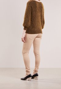 Brun fluffig tröja med ballongsärmar, i kombination med slim-fit beige byxor och svarta klackar med silverblock.