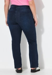 Jeans de mezclilla azul oscuro con un diseño de pierna recta, que cuentan con dos bolsillos traseros y una cinturilla alta. Tejido texturizado.
